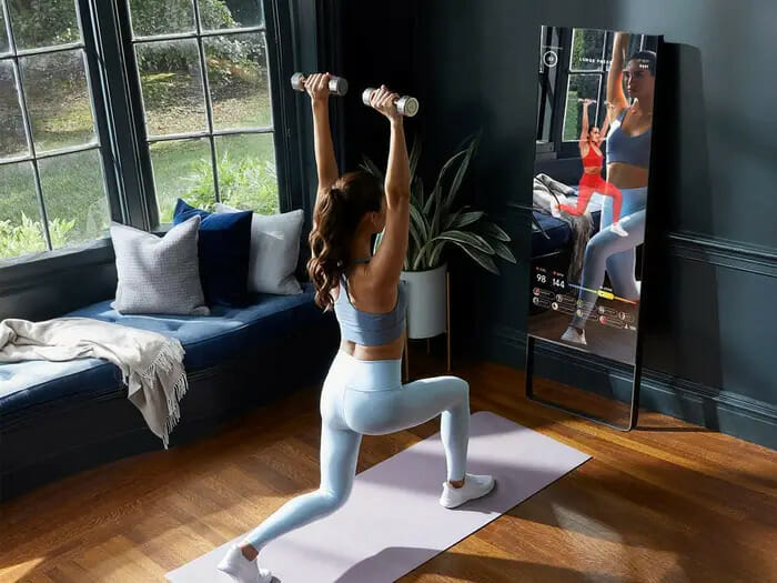 A woman working out in front of a smart mirror wearing Lululemon clothing.