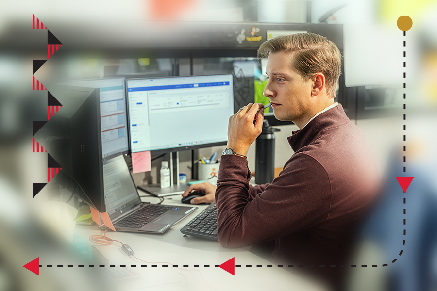 businessman simultaneously viewing WMS on a laptop screen and an ERP on two monitors